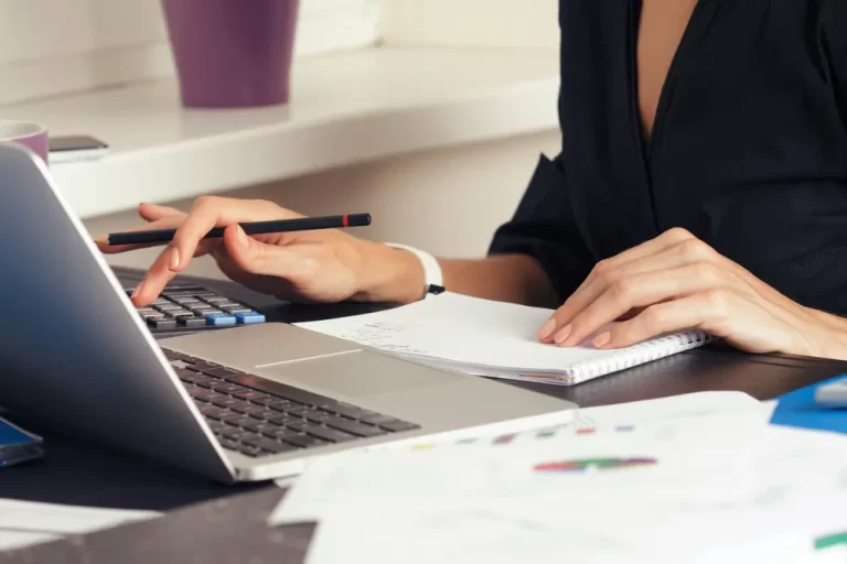 Real-time bookkeeping | Person typing on calculator and laptop.