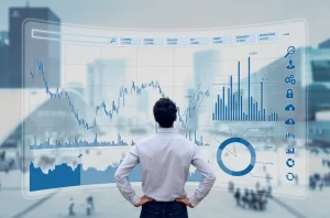 Financial specialist | A person standing with their back to the camera, looking at financial graphs on a large screen.
