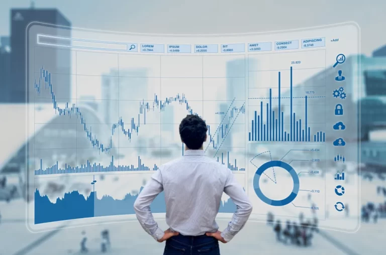 Financial specialist | A person standing with their back to the camera, looking at financial graphs on a large screen.