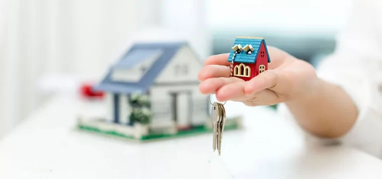 Property investments | Person holding a miniature house model.