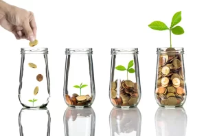 Business planning | 4 glass jars with progressively more coins inside, with a small green leafy plant growing in each one.