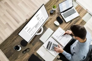Local accountant | Person sitting at desk working on computer with documents in front of them.